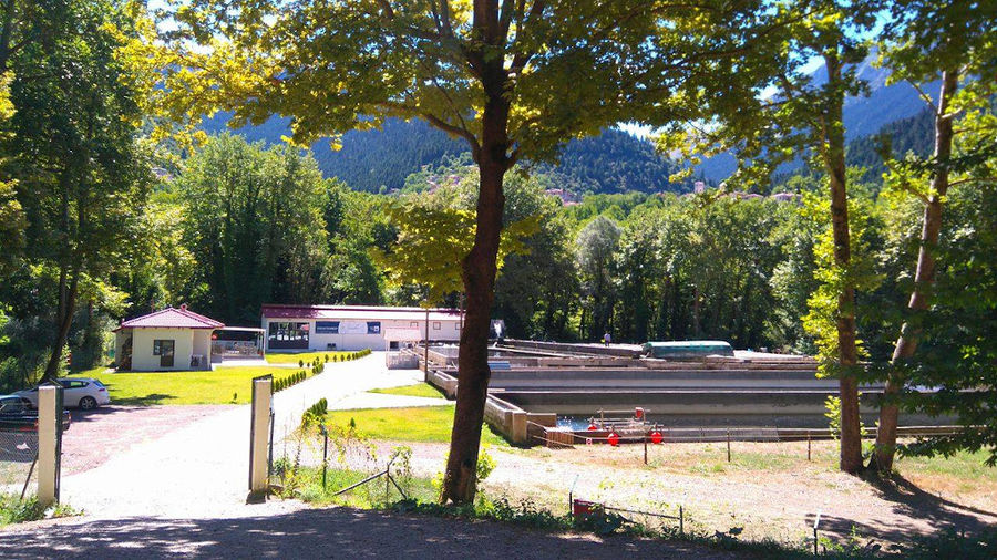 far view of ponds fish crops and buildings surrounded by trees and mountains at 'Fresko'